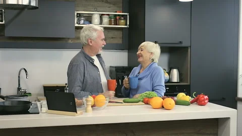 Happy elder couple drinking coffee and talking at the kitchen. Stock Footage 102216321