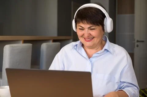 Happy elder woman with headset using laptop for education,work,online shoppin Stock Photos