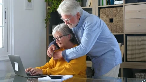 Happy elderly 60s couple sit rest on couch at home pay household expenses online Stock Footage 152111330
