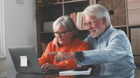 Happy elderly 60s couple sit rest on couch at home pay household expenses online Stock Footage 152111336