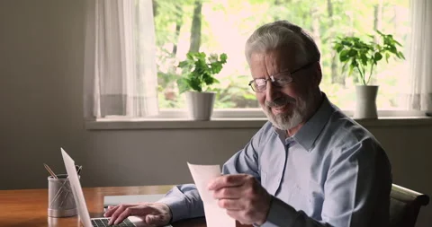 Happy elderly 60s man paying utility bills online on computer. Stock Footage 147511472
