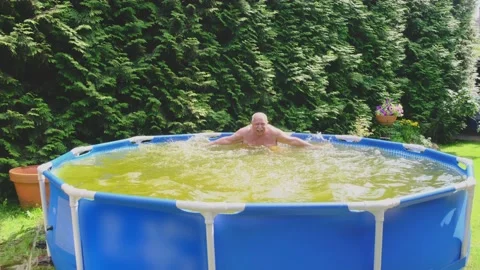 Happy elderly bald man moves arms splashing pool water Stock Footage 136776253