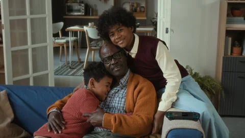 Happy Elderly Black Man Hugging Grandchildren while Sitting on Sofa Stock Footage 322527255