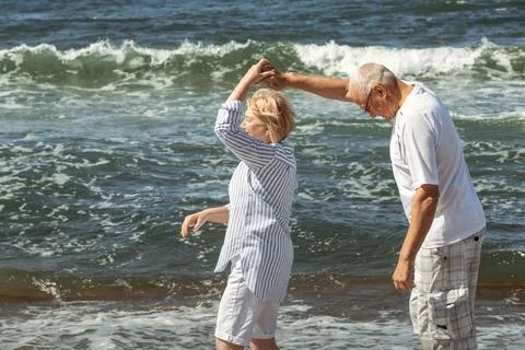Happy elderly couple dancing on the seashore. Stock Photos