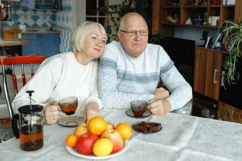 Happy elderly couple drinking tea with sweets together at home Fotos Stock