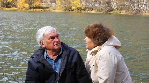 Happy elderly couple sitting and talking on the lake Stock Footage 32056236
