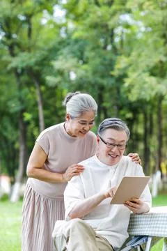 Happy elderly couples use tablet computers to surf the Internet outdoors Stock Photos