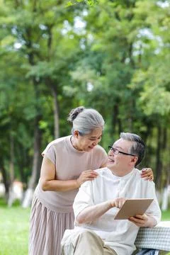 Happy elderly couples use tablet computers to surf the Internet outdoors Stock Photos