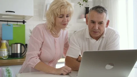 Happy elderly family using computer in apartment kitchen. Stock Footage 103654085