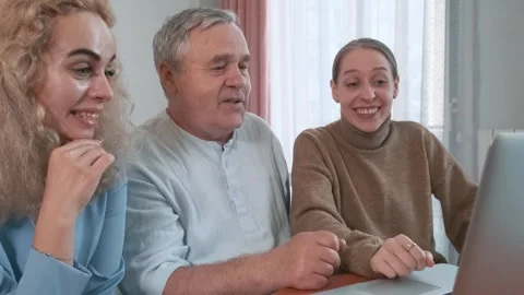Happy elderly father with two daughters laughing while watching laptop together Stock Footage 315861337