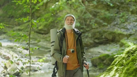 Happy Elderly Man with a Backpack and Nordic Walking Sticks Hiking in the Forest Stock Footage 163761813