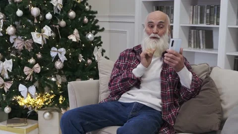 Happy elderly man with grey spade beard smiles looking in phone and surprise Stock Footage 224530394