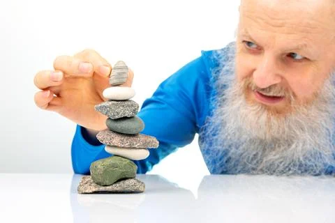 Happy elderly man with a long gray beard stacking a variety of smooth and t.. Stock Photos