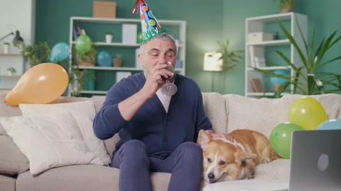 Happy Elderly Man in a Party Cap with a Glass of Wine Celebrates Online Stock Footage 166729386
