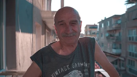 Happy elderly man waving hand on balcony with superb sun flare.  Stock Footage 109418191