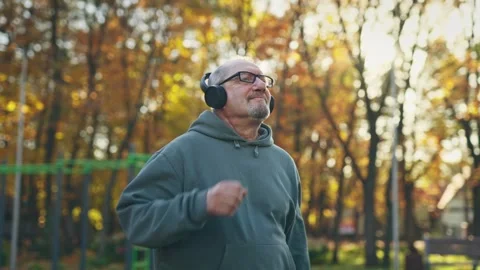 Happy elderly man working out. Funny senior man wearing headphones exercising Stock Footage 255295021