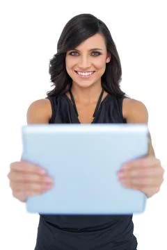 Happy elegant brown haired model holding tablet in front of her Stock Photos