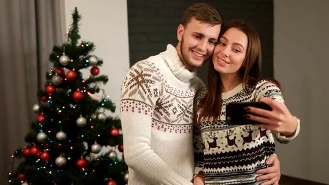 Happy emotional couple in love posing on smart phone camera on christmas tree Stock Footage