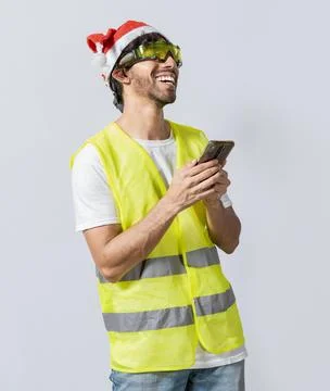 Happy Engineer in christmas hat using cell phone isolated. Smiling engineer.. Stock Photos