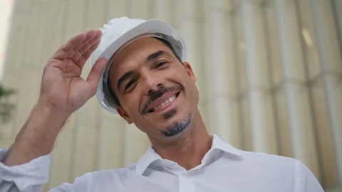 Happy engineer posing modern architecture portrait. Latin man taking off hardhat Stock Footage 265310181