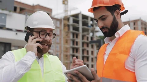 Happy engineer speaks on Mobile phone on construction site and checks the work Stock Footage 110778722