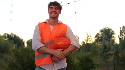 Happy engineer taking off and holding a protective helmet, posing near high Stock Footage 252267017