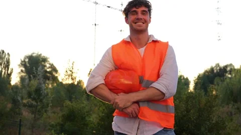 Happy engineer taking off and holding a protective helmet, posing near high Stock Footage 255391167
