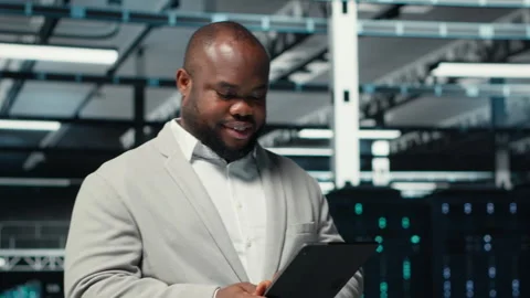 Happy engineer walking in data center refining algorithms on tablet Stockbeeldmateriaal 311962420