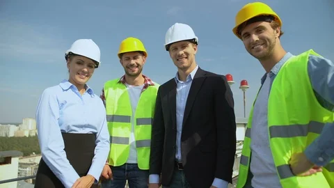 Happy engineers and workers in helmets smiling on camera, construction service Vídeo Stock 117217486