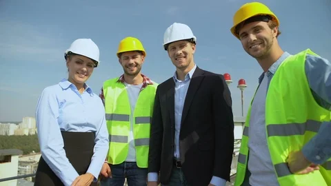 Happy engineers and workers in helmets smiling on camera, construction service Видео 117218809