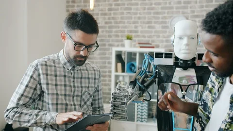 Happy engineers testing robot in office working with modern machine indoors Stock Footage 119579168