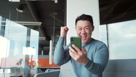 Happy euphoric asian man freelancer, employee, worker celebrate mobile win,  Stock Footage 166233247