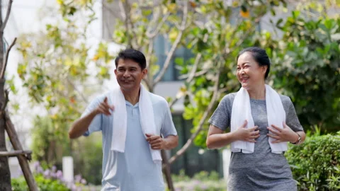 Happy family Asian elderly couple jogging in the village garden. Stock Footage