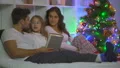 The happy family with a book laying on the bed near a christmas tree 4k or 4k+ Resolution