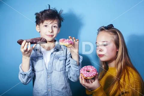 Happy family brother and sister eating donuts on blue background, lifestyle Stock Photos