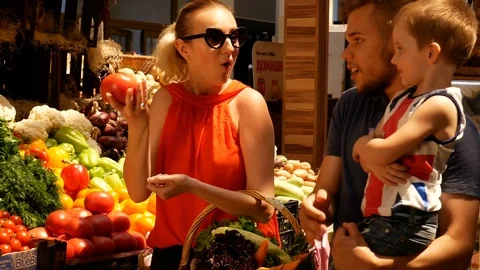 Happy family choose tomatoes at the market Stock Footage