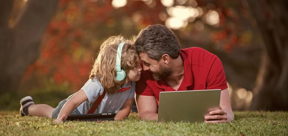 Happy family of dad and son use laptop for lesson listen music in headphones in Stock Photos