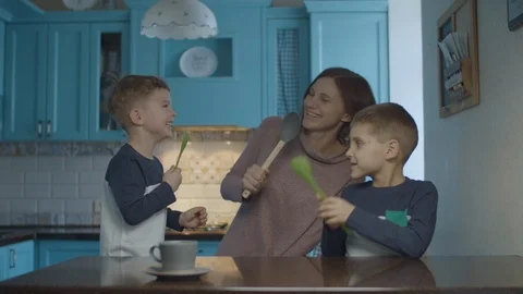 Happy family dancing and singing into kitchenware like a microphone on kitchen Stock Footage