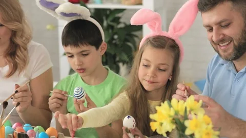 Happy family decorating Easter eggs sitting at the table Stock Footage 89876127