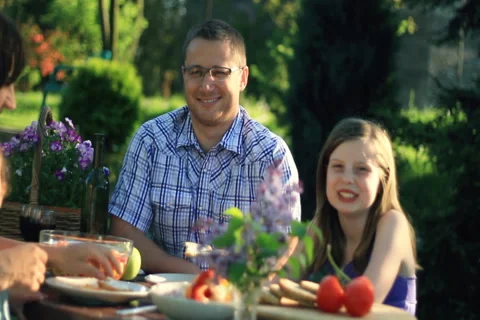 Happy family eating breakfast, meal in the garden, dolly shot NTSC wide Stock Footage
