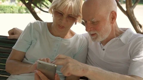 Happy family enjoying vacation in Europe. Seniors sitting on bench in park Stock Footage