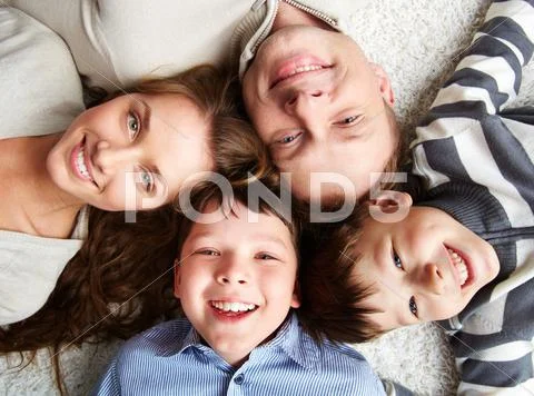 A happy family of father, mother and their adorable kids looking at camera Stock Photos