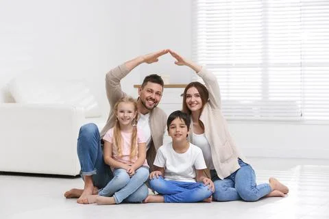 Happy family forming house roof with their hands at home. Insurance concept Stock Photos