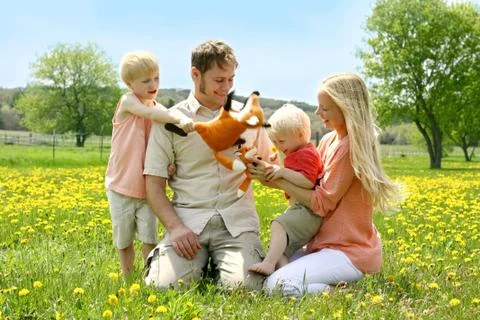 Happy family of four people playing with toys outside in flower meadow Stock Photos