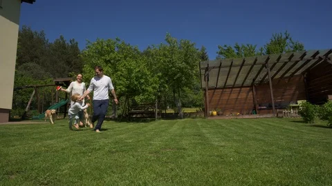 Happy family mother father and son with dogs pets run though yard. Handheld shot Stock Footage