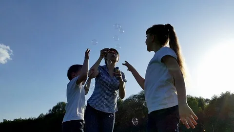 A happy family in nature lets bubbles blow. Mom and children rest on a picnic Stock Footage