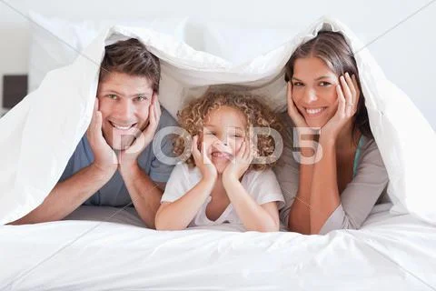 Happy family posing under a duvet Stock Photos