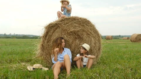 Happy family resting near a haystack on a grass field. Farmer family walking Stock Footage
