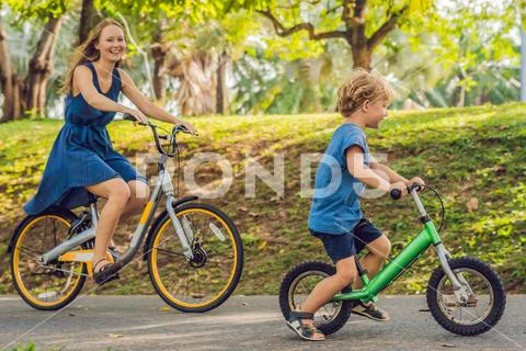 Happy family is riding bikes outdoors and smiling. Mom on a bike and son on a Stock Photos