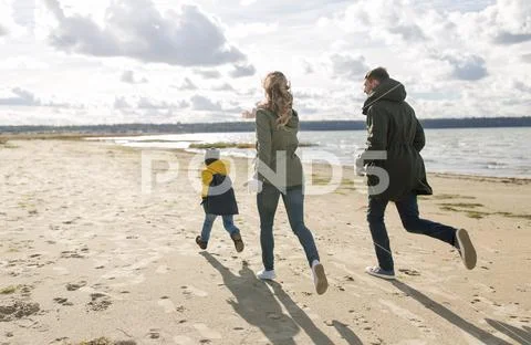 Happy family running along autumn beach Stock-Fotos